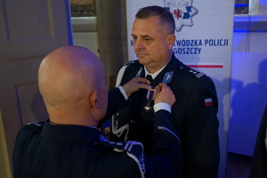 policjant przypina do munduru funkcjonariusza medal