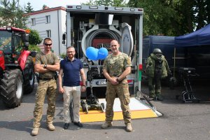 policjanci pozuja do zdjęcia z uczestnikiem festynu