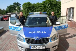 dwóch policjantów stoi przy radiowozie