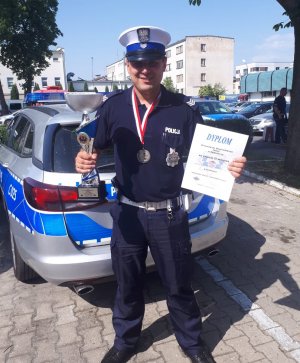 policjant stoi i trzyma w rekach puchar i dyplom