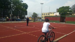 policjant na boisku obserwuje jadącego na rowerze uczestnika egzaminu