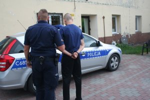 policjant prowadzi zatrzymanego