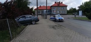 samochód bmw, który znajduje się cześciowo na chodniku, a częściowo na posesji