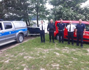 policjanci i strażacy stojący nad jeziorem