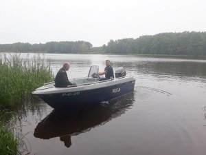 policjant wspólnie ze strażakiem pływa łodzią po jeziorze