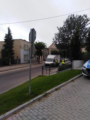 policjant stoi przy samochodzie i bada stan trzeźwości kierujacego