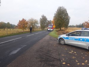 policjanci zabezpieczają drogę na której rozstawiły sie wozy strażackie