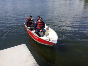 policjnat i strażacy pływają łódka po jeziorze