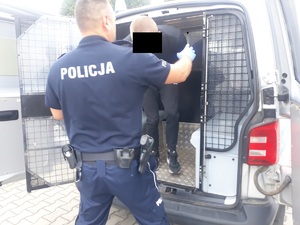 policjant wyprowadza zatrzymanego z radiowozu