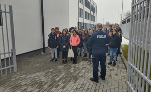 policjant z uczestnikami spotkania stoją na zewnątrz komendy policji