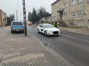 policjant na drodze stoi przy pojezdzie i sprawdza stan trzeźwości kierowcy