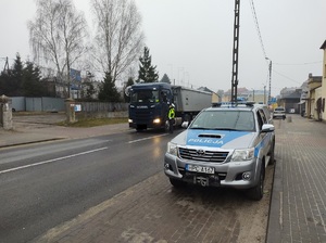 policjant na drodze stoi przy pojezdzie i sprawdza stan trzeźwości kierowcy