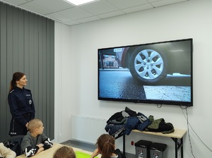 policjantka wspólnie z dziećmi odgląda prezentowane filmy na ekranie telewizora