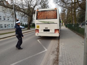 policjant stoi za autokarem i sprawdza oświetlenie