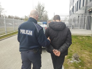 policjant prowadzi zatrzymanego