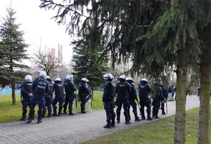 policjanci stoja przy chodniku i zabezpieczają przejście kibiców
