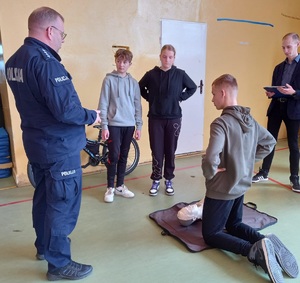 policjant nadzoruje zadanie z udzielnia pierwszej pomocy