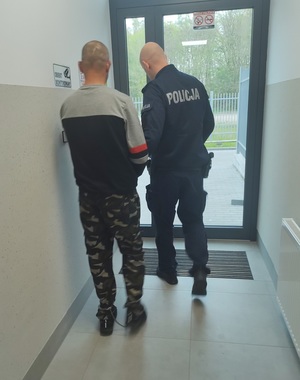 policjant prowadzi zatrzymanego