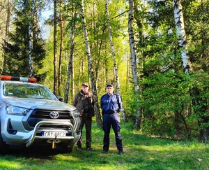 policjant i strażnik leśny stoja przy radiowozie