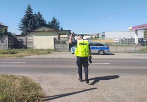 policjant na drodze daje znak reka do zatrzymania pojazdu