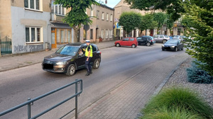 policjant przy samochodze sparwdza trzeźwość kierowcy