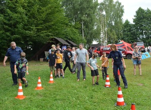 dzieci wspólnie z policjantami pokonuja slalom z alkogoglami