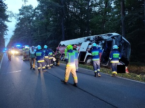 autokar w rowie, na drodze stoja strażacy