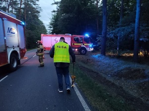 policjant przeprowadza oględziny mierzac drogę