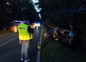 policjant robi oględziny na drodze z wózkiem do mierzenia