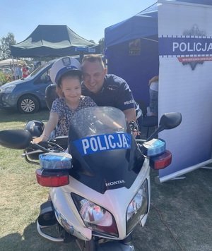 dziewczynka siedzi na policyjnym motocyklu, przy niej policjant