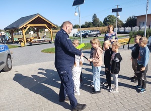 policjant wsolnie z dziecmi przed przejściem dla pieszych