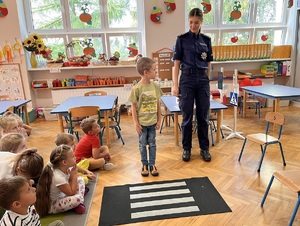 policjantka stoi z dzieckiem przed mata imitująca przejście dla pieszych