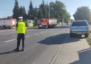 policjant na drodze kieruje ruchem ułatwiając przejazd strazy pożanej