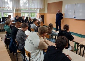 policjant stoi przed uczniami i prowadzi prelekcję
