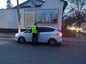 policjant stoi przy zatrzymanym pojeździe