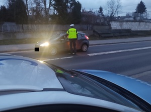 policjant na drodze stoi przy zatrzymanym pojeździe