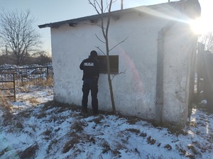 policjant zaglada przez okno do budynku