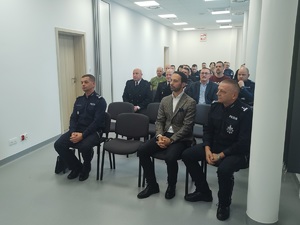 zdjecie wszystkich uczestników odprawy, którzy siedza na krzeslach