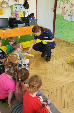 policjantka zakłada dzieciom opaski odblaskowe na ręke