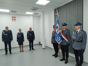 zastepca komendanta Wojewódzkiego oraz komendant Powiatowy policji w rypinie wraz z zastępcą stoja na tle godła, obok stoi poczet sztandarowy