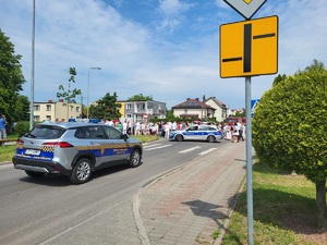 radiowóz stojący na drodze zabezpieczający przechodzacych ludzi