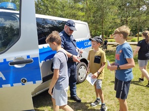 policjant przy radiowozie i kilka osób z ktorymi rozmawia