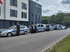 przed budynkiem jednostki policji ustawione sa radiowozu, przy których stoja policjanci