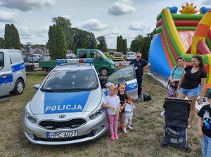 uczestnicy pikniku stoją przy radiowozie