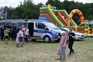 uczestnicy pikniku stoja przy radiowozach i rozmawiają z policjantami