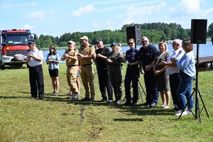 organizatorzy wyderzania stoja w jednym szeregu na plazy przy jeziorze