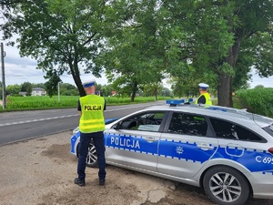 policjanci stoja przy drodze i mierza predkośc pojazdów