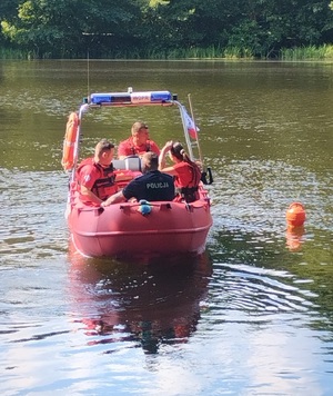 łódź wopr-u w której siedzą ratownicy i policjant