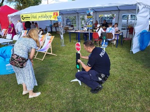 policjant pokazuje dziecim znaki drogowe