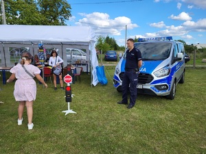 policjant stoi przy dzieciach przy znakach drogowych, w tle stoi radiowóz